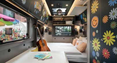 View of Interior of Camper Flower Coco with bed, guitar and windows