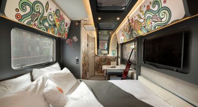 Interior of the camper Hippie Coco with small table, guitar, sleeping area and colorful wall covering 