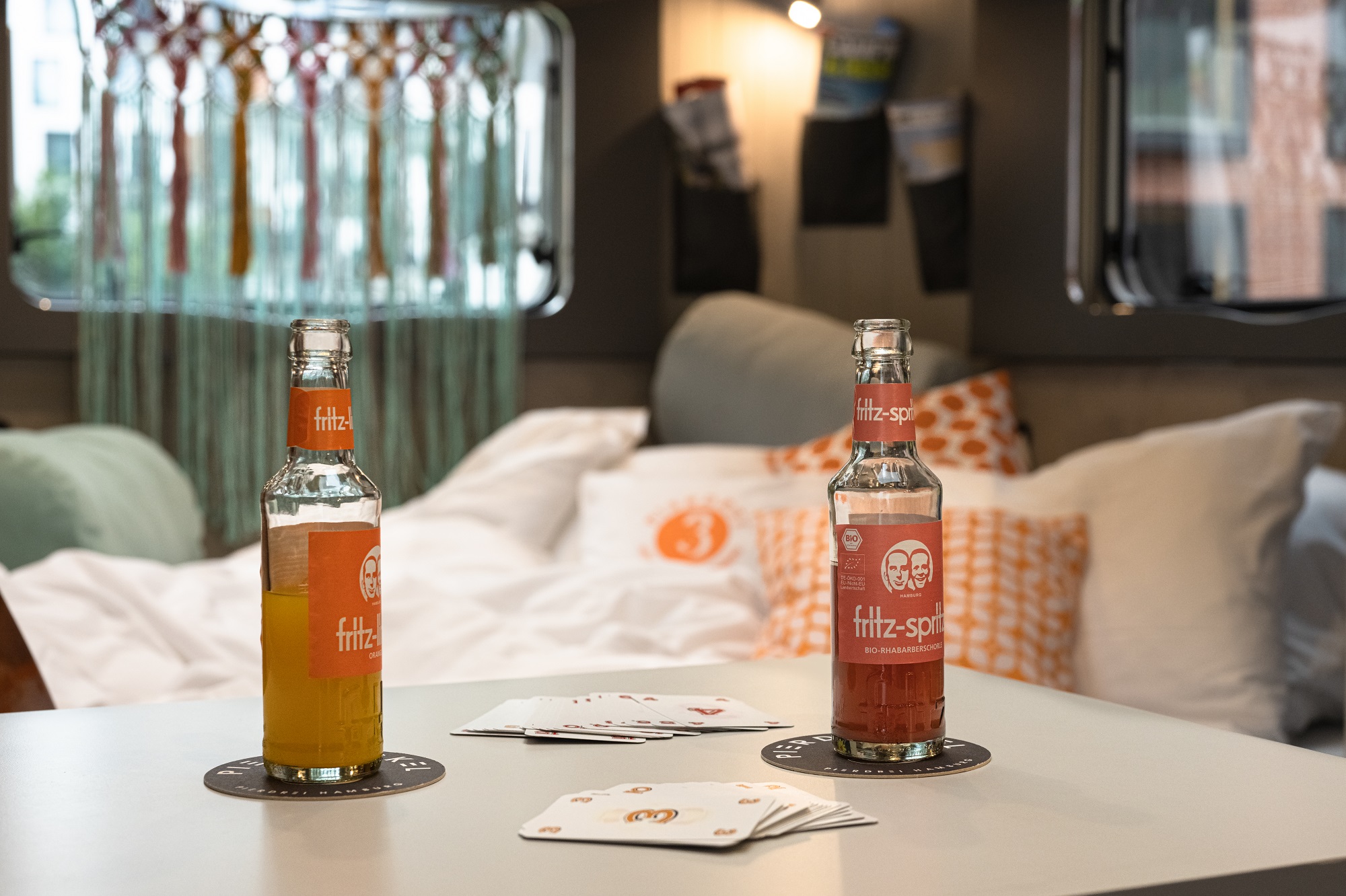 Nahansicht des Tisches im Camper Flower Coco mit zwei Fritz Getränken und Bett im Hintergrund