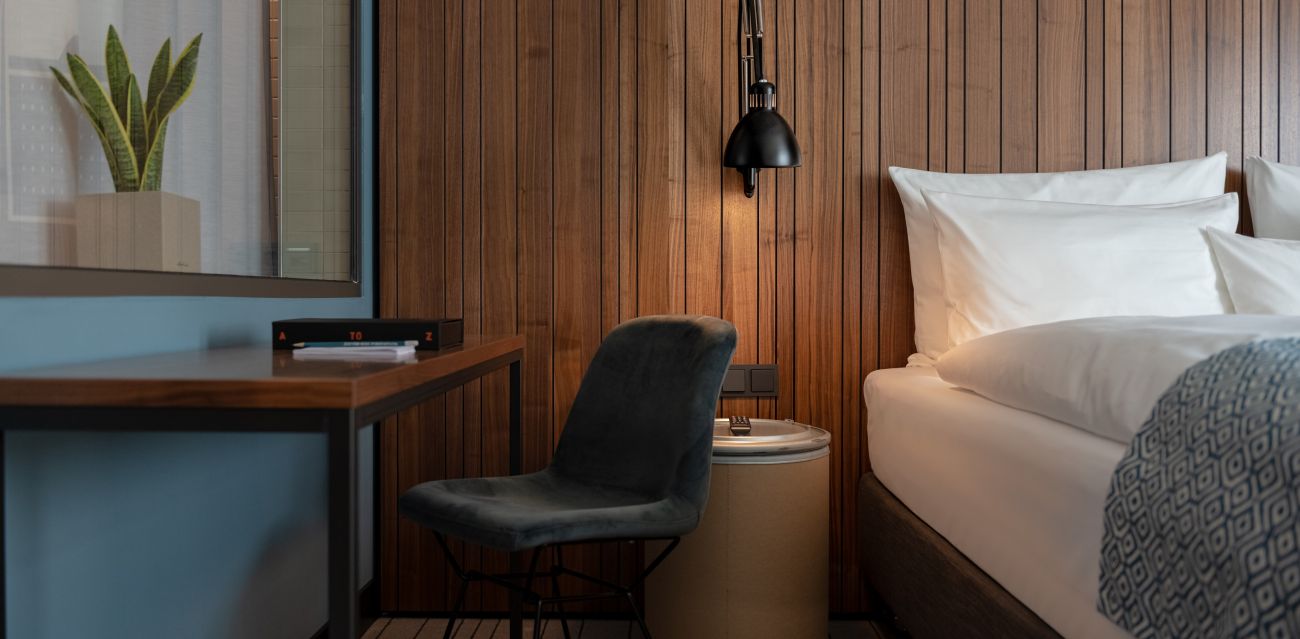 Bed with wooden wall behind it and window with curtain to the bathroom in a room of category MEDIUM PLUS