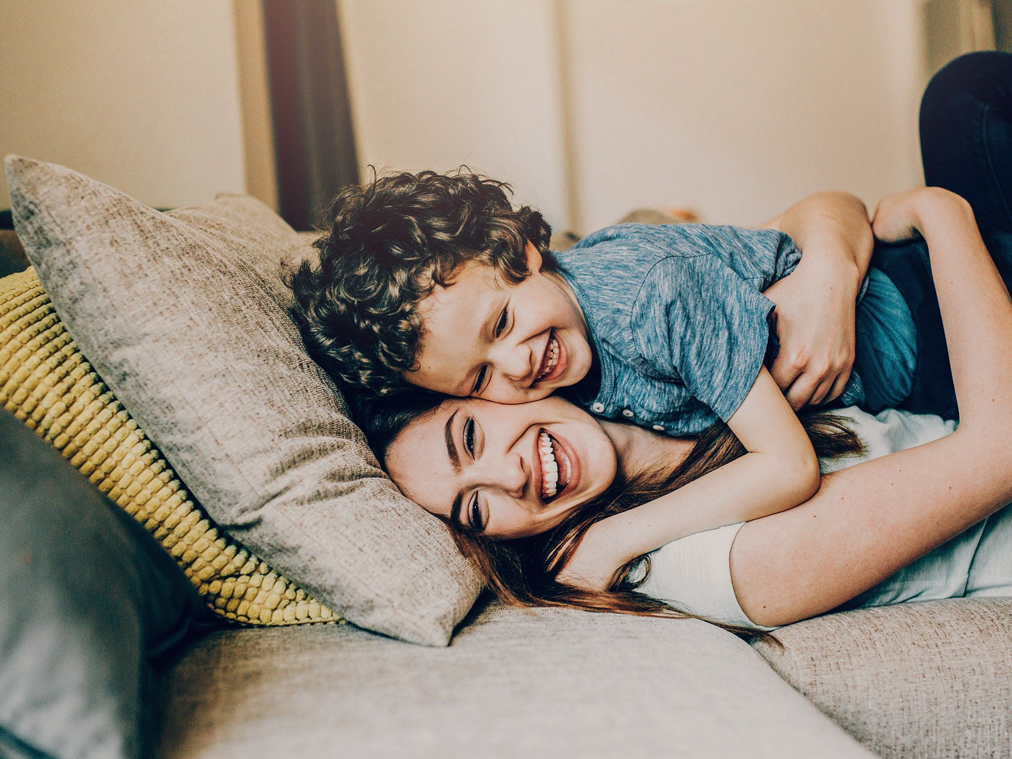 Fröhliche Mutter mit Kind im Familienhotel beim toben auf dem Bett im PIERDREI