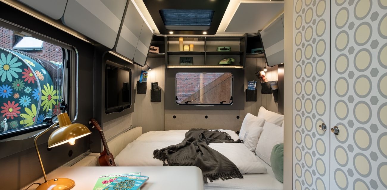 View of the interior of the camper RETRO with small table and extended bed, stickers in retro style and retro decoration